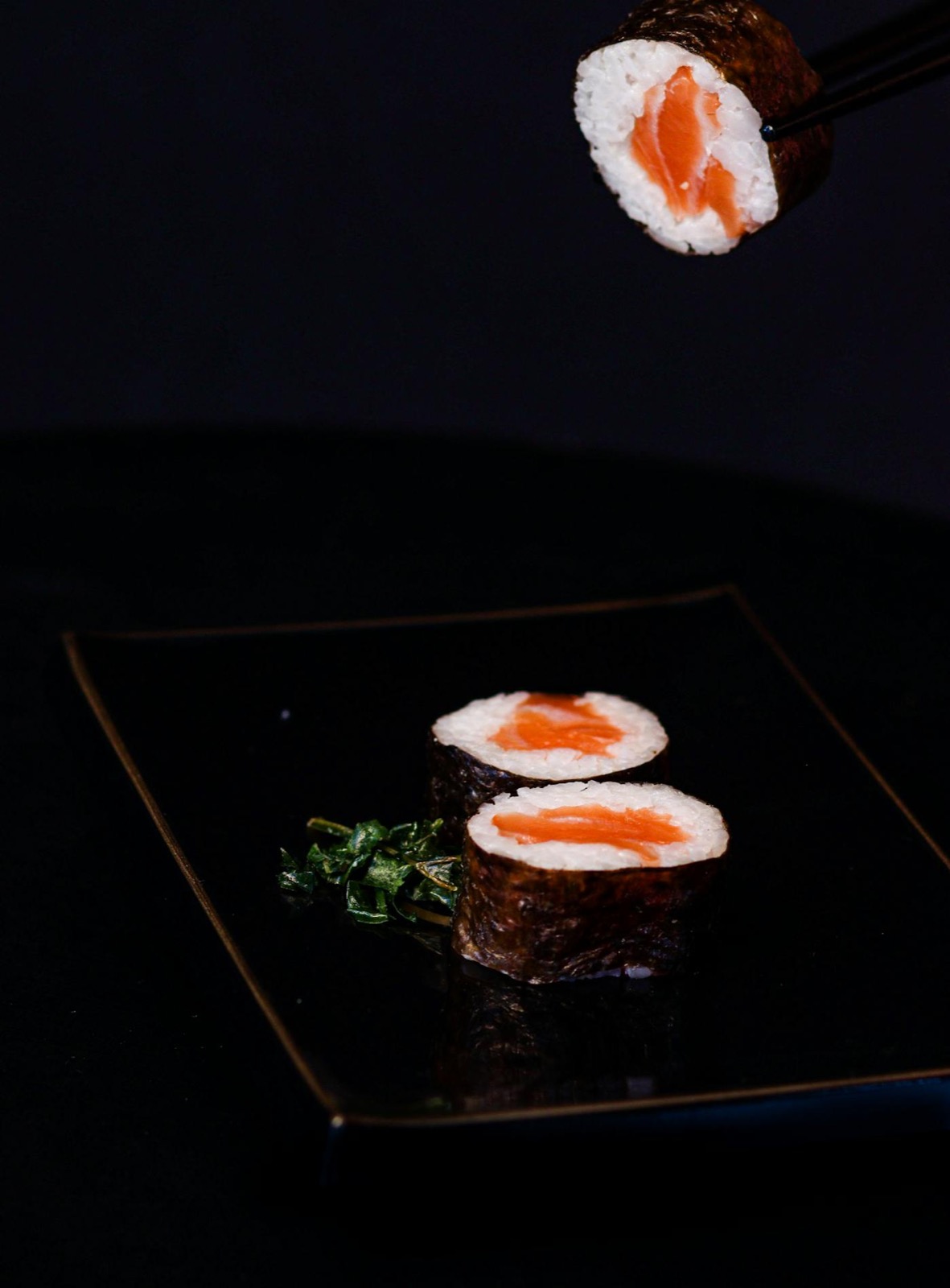 Dîner sushi à La Jetée Juan-les-Pins — maki saumon sur assiette laquée noire et or, baguettes japonaises, ambiance soir